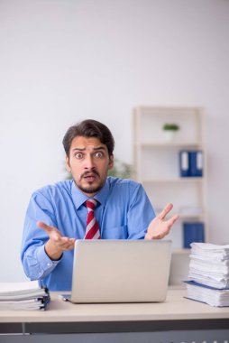 Ofisteki aşırı işten memnun olmayan genç bir erkek işçi.