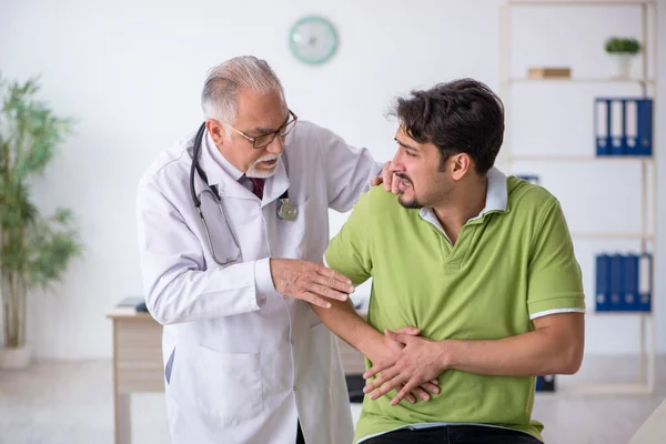 Jovem paciente masculino visitando velho médico masculino — Fotografia de Stock