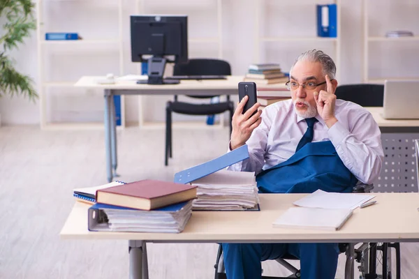 Egy öreg férfi tolószékben ül az irodában. — Stock Fotó