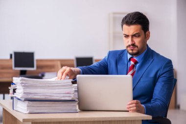 Genç erkek çalışan işyerinde aşırı çalışmaktan memnun değil.