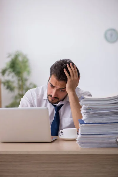 Jovem funcionário masculino infeliz com excesso de trabalho no escritório — Fotografia de Stock