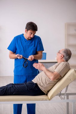 Yaşlı erkek hasta, genç doktor.