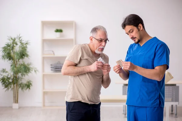 Vecchio paziente maschio visting giovane medico maschio — Foto Stock