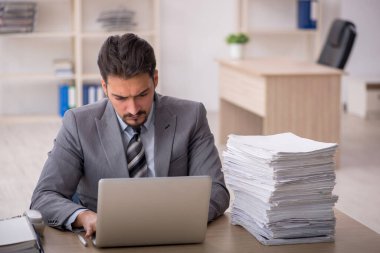 Ofisteki aşırı işten memnun olmayan genç bir erkek işçi.