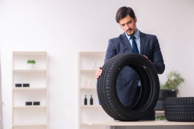 Genç adam ofiste lastik satıyor.