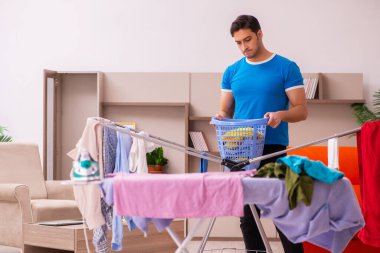 Genç adam evde ütü yapıyor.