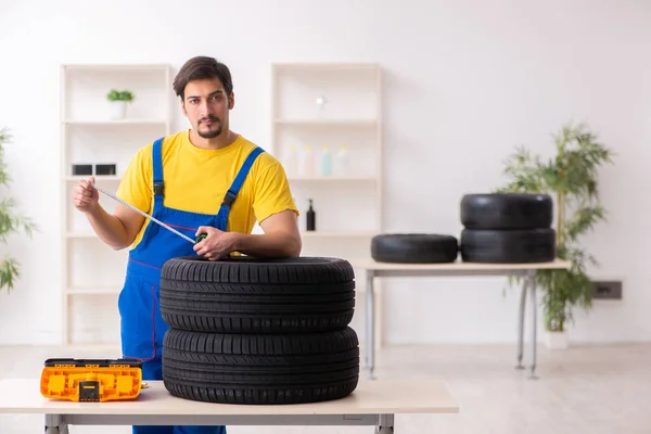 Joven trabajador de garaje con neumático en el taller —  Fotos de Stock