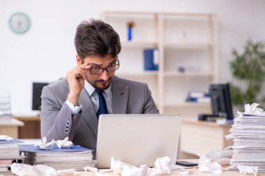 Genç bir erkek çalışan ve ofiste çok fazla iş var.
