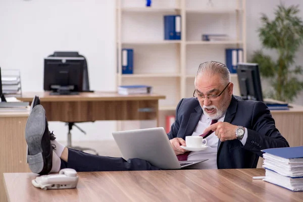 Gammal manlig anställd dricker kaffe under rasten — Stockfoto