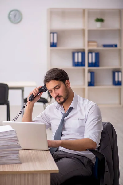 Joven empleado masculino y demasiado trabajo en la oficina —  Fotos de Stock