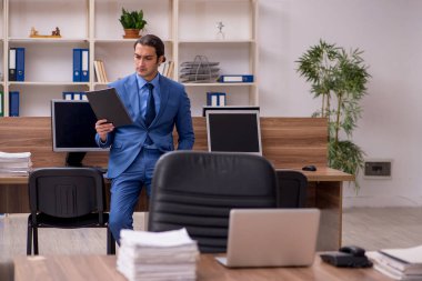 Genç bir erkek çalışan ve ofiste bir sürü iş var.