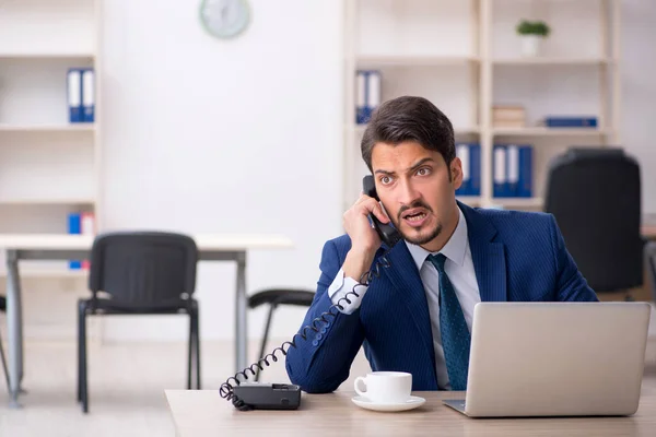 Joven empleado masculino y demasiado trabajo en la oficina — Foto de Stock