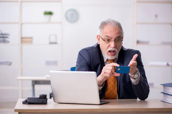 Stary pracownik posiadający kartę kredytową w biurze — Zdjęcie stockowe