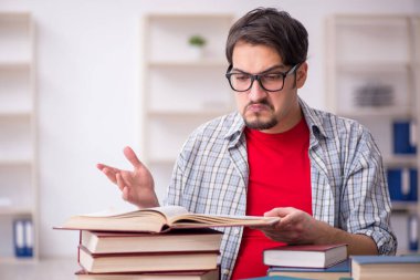 Genç bir erkek öğrenci ve sınıfta çok fazla kitap var.