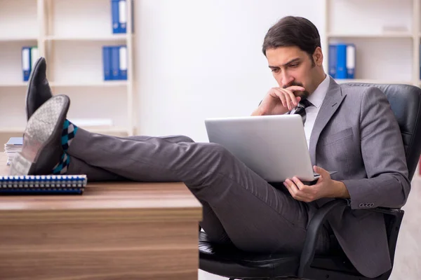 Joven empleado masculino atractivo sentado en el lugar de trabajo — Foto de Stock