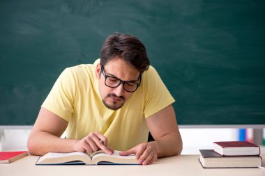 Tahtanın önünde genç bir erkek öğrenci.