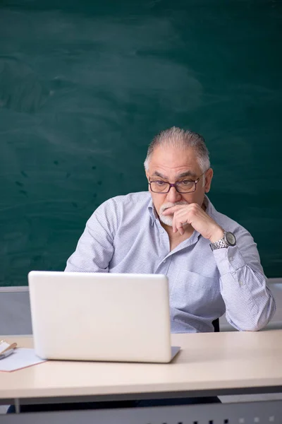 Gammal manlig lärare framför green board — Stockfoto