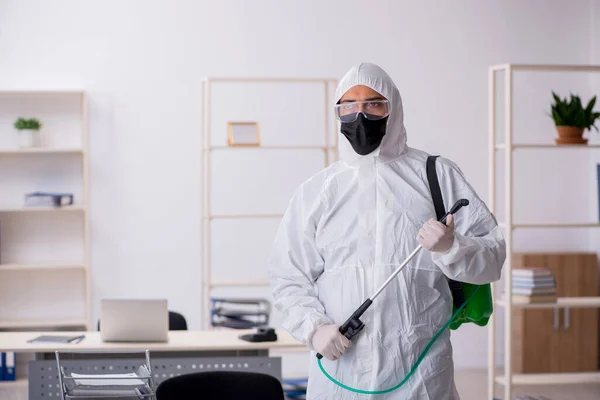 Young male contractor disinfecting office during pandemic — Stock Fotó