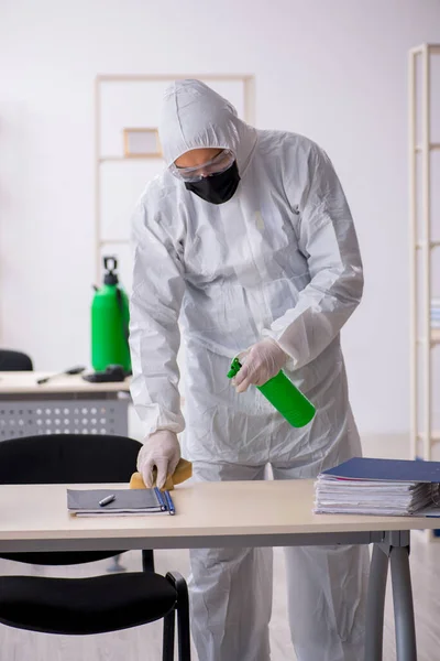 Young male contractor disinfecting office during pandemic — Stock Photo, Image