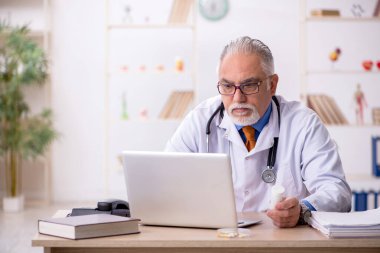 Klinikte çalışan yaşlı erkek doktor.