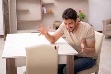 Genç adam ve evde bir sürü hamamböceği var.