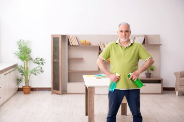 Yaşlı adam evi temizliyor.