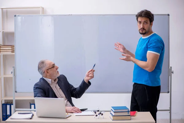 Oude mannelijke leraar en jonge mannelijke student in de voorkant van whiteboard — Stockfoto