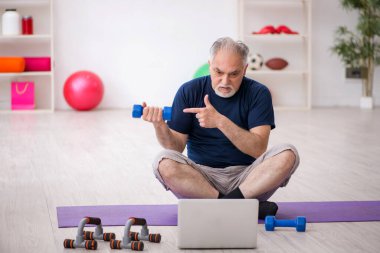 Yaşlı adam içeride spor egzersizleri yapıyor.