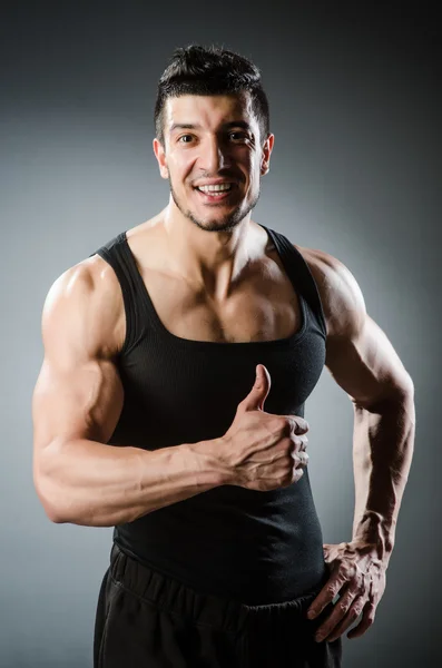 Muscular man posing in dark studio — Stock Photo, Image