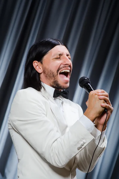 Homem cantando na frente da cortina no conceito de karaoke — Fotografia de Stock