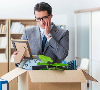 Ofisi kutu ve eşyalarıyla taşıyan bir adam.