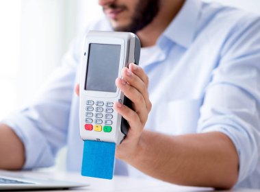 POS terminali ile kredi kartı işlemi yapan adam