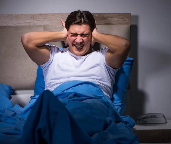 Jongeman worstelt met lawaai in bed — Stockfoto