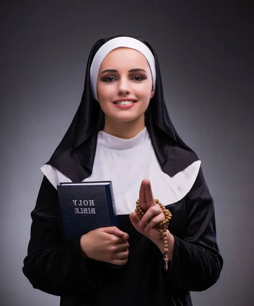 Religieuze nun in religie concept tegen de donkere achtergrond — Stockfoto