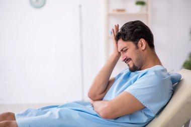 Genç erkek hasta hastanede doktor bekliyor.