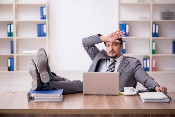 Joven empleado masculino atractivo sentado en el lugar de trabajo — Foto de Stock