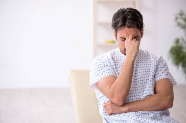 Genç erkek hasta hastanede doktor bekliyor.