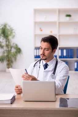 Klinikte çalışan genç erkek doktor.