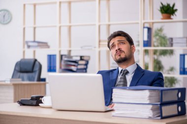 Genç bir erkek çalışan ve ofiste çok fazla iş var.