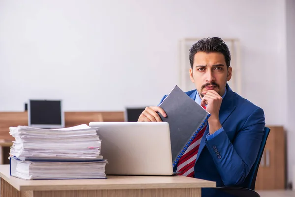 Jonge mannelijke werknemer ongelukkig met buitensporig werk op de werkplek — Stockfoto