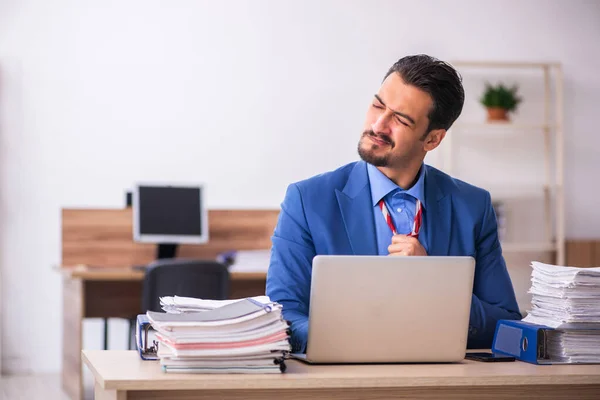 Jovem trabalhador masculino infeliz com excesso de trabalho no local de trabalho — Fotografia de Stock