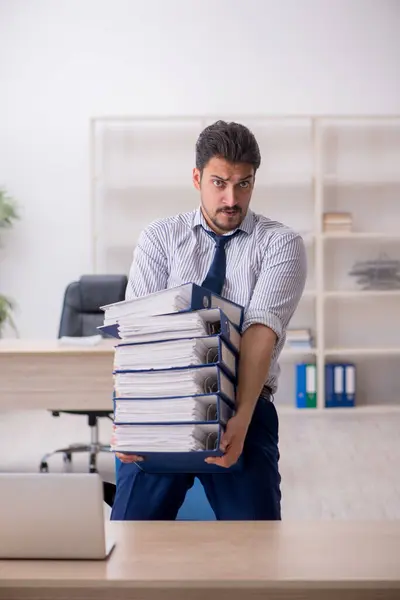 Joven empleado masculino y demasiado trabajo en la oficina — Foto de Stock