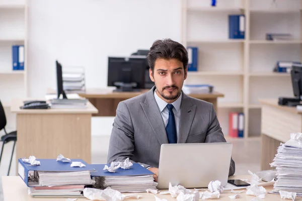 Young male employee and too much work in the office — Stock Photo, Image