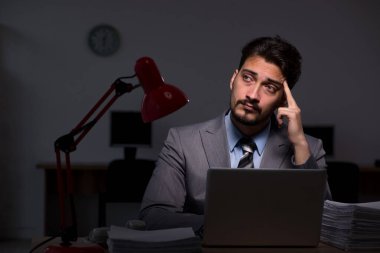 Genç erkek çalışan ofiste geç saatlere kadar çalışıyor.