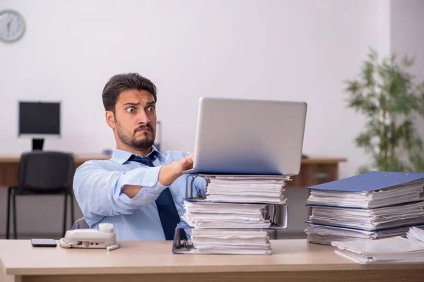 Ung manlig anställd och för mycket arbete på kontoret — Stockfoto