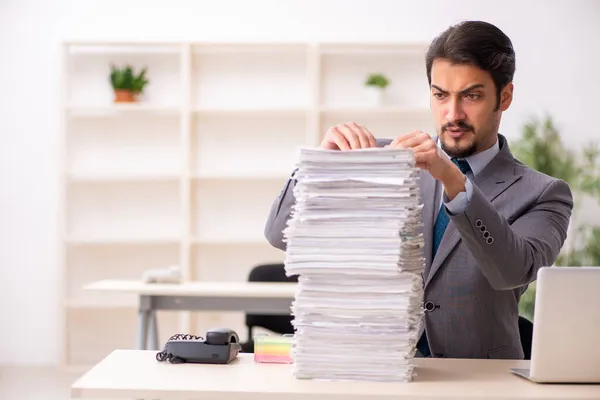 Jonge mannelijke werknemer ongelukkig met overmatig werk in het kantoor — Stockfoto