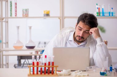 Laboratuvarda bilgisayar başında oturan genç bir kimyager.