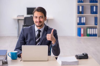 Genç erkek çalışan işyerinde oturuyor.