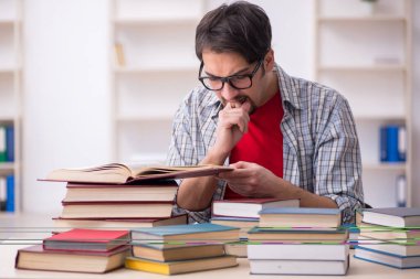 Genç bir erkek öğrenci ve sınıfta çok fazla kitap var.