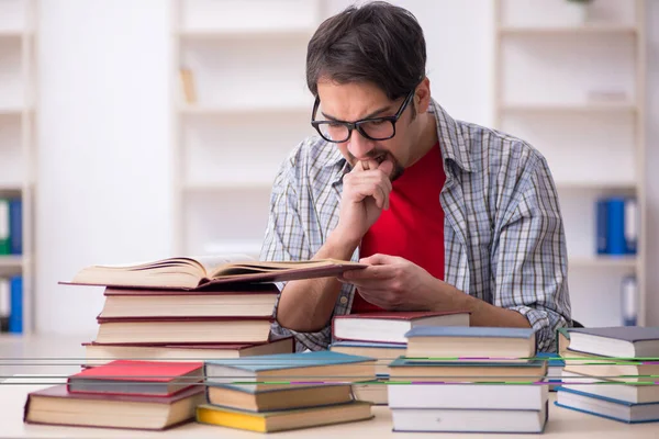 Young male student and too many books in the classroom — Stock Photo, Image